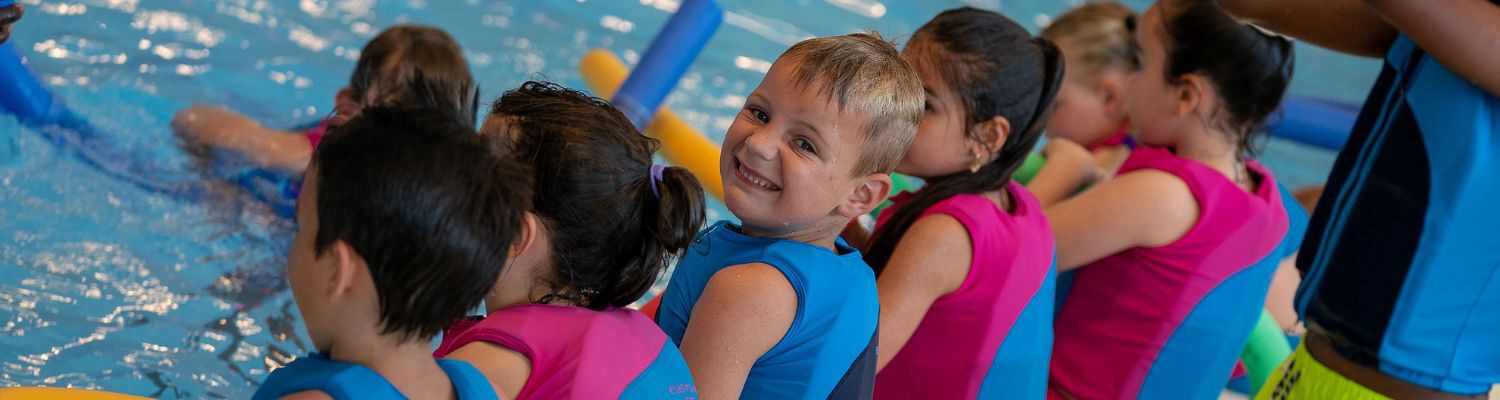 Kinderen tijdens de zwemles die op de zwembadrand zitten