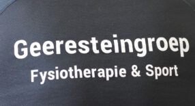 je ziet de rug van een fysiotherapeut in Amerena. Op zijn rug staat: Geeresteingroep Fysiotherapie en Sport