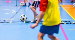 Voetballende kinderen in een sportzaal