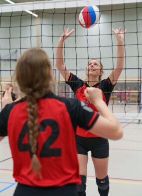 2 volleybalsters van Volleybalvereniging Wilhelmina spelen de bal over het net